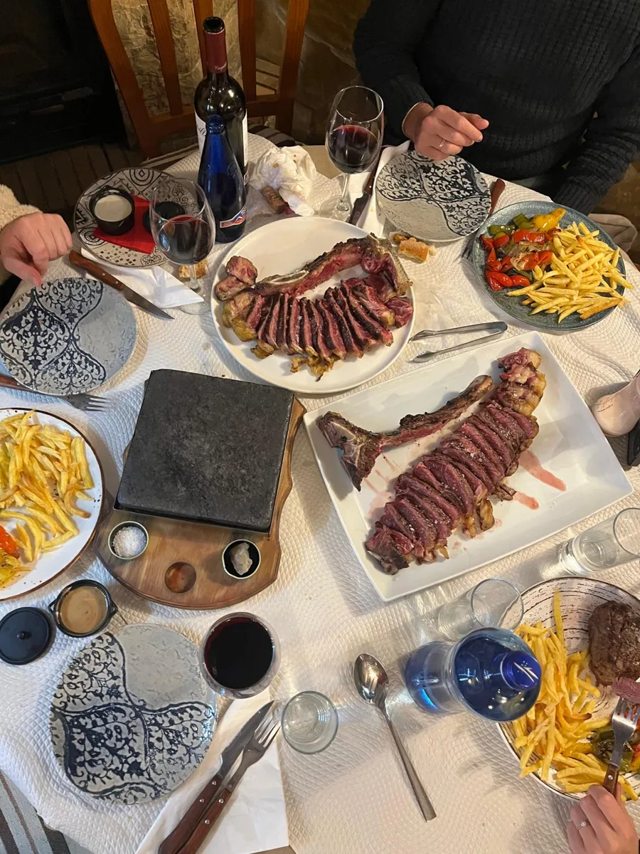Mesa con T-bone a la piedra, patatas y vino